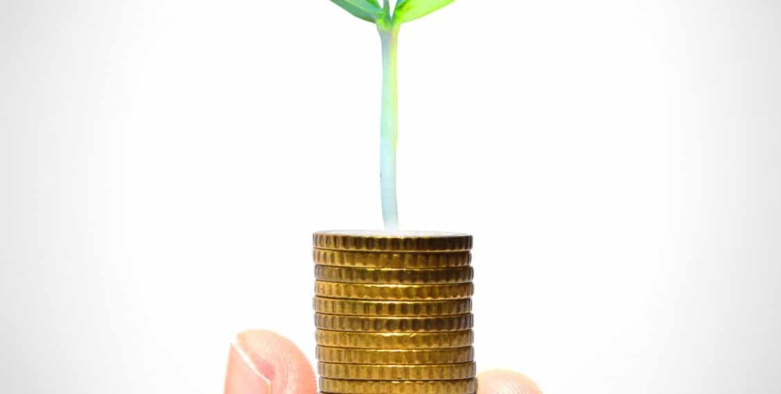 Businessman holding plant sprouting from a handful of golden coi